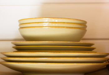 A stack of plates and bowls with a rustic, warm tone are arranged, ready for a dining or home...