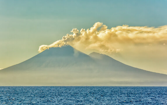 Active Volcano, Coral Sea, Papua New Guinea. Active volcano puffing smoke at sunrise.