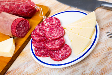 Healthy spanish snack tapas, slicing sausages and cheeses served on black plate