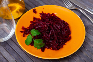 Tasty vitamin salad of sweet grated boiled beets with olive oil and greens. Vegetarian appetizer..