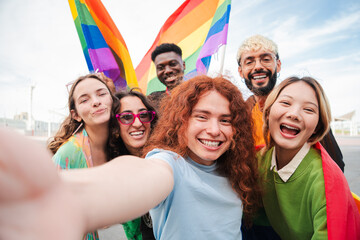 Joyful diverse friends celebrating together with rainbow flags during pride festivities while...