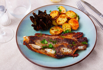 Popular dish of Spanish cuisine is beef churasco with delicious fried potatoes and artichokes, decorated with fresh herbs ..on top