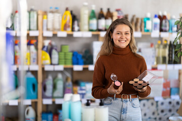 Young woman buyer chooses blush and sculptor palette in household chemicals store
