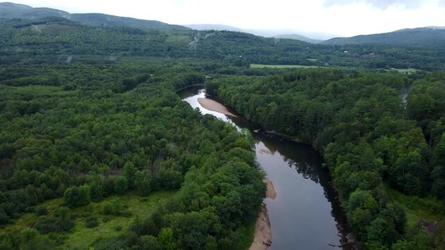 Aerial cinematic video of the Pemigewasset River winding through a dense forest near Franconia Notch in the White Mountains of New Hampshire