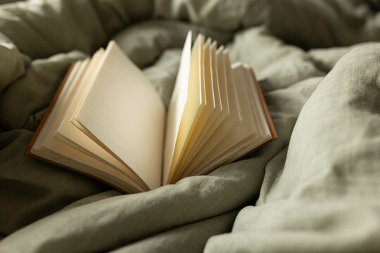 close-up of an open blank journal on a soft light green blanket in natural light