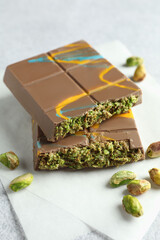 Pieces of Dubai chocolate bar with pistachios and knafeh on light grey table, closeup
