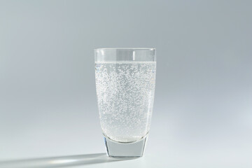 Refreshing soda water in glass on light grey background