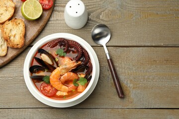 Delicious seafood soup served on wooden table, flat lay. Space for text