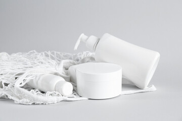 Many cosmetic products and mesh bag on light grey background