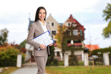 Real estate agent holding clipboard near house outdoors