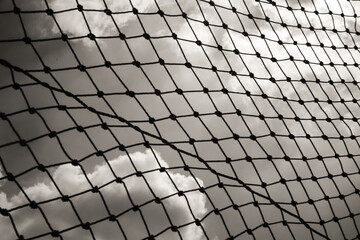 Abstract monochrome goal net with cloud background. Panorama landscape of knot rope in balck and white. Shadow and silhouette. Sports and entertainment. Textured Wallpaper. Copy space