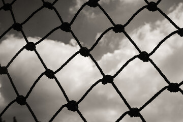 Fototapeta premium Abstract monochrome goal net with cloud background. Panorama landscape of knot rope in balck and white. Shadow and silhouette. Sports and entertainment. Textured Wallpaper. Copy space