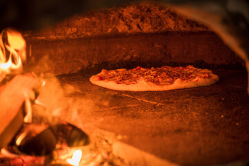 An organic pizza cooks in a wood fired oven.