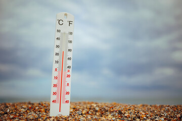 Thermometer in the Sand at the Seaside with Moderate Temperature. Pleasant holiday day with...