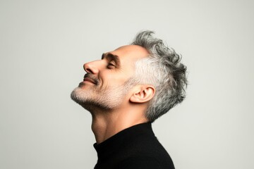 Fototapeta premium Pure white solid background. A serene and handsome man posing in style. Visual idea art of style for aging men. Fashionable men's buzz cut haircut - midlife white man with grey hair.
