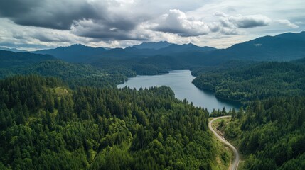 Mountain lake aerial view, winding road, cloudy sky, lush forest
