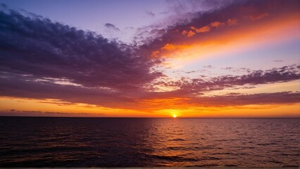 Obraz premium Fiery Skies Over Calm Waters: An Ocean Sunset with Dramatic Clouds Displaying Vivid Colors and Reflections.