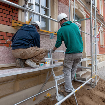 Handwerker auf Bauger&uuml;st bei Restaurierungsarbeiten an einer Fassade