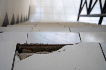 Damaged Tile Stairway with Broken Edges and Visible Concrete Indoors