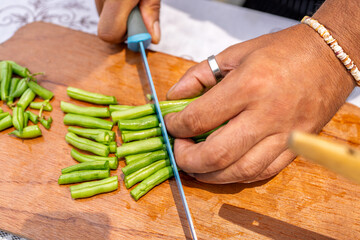 Obraz premium Chef chopping green beans on wooden cutting board for paella