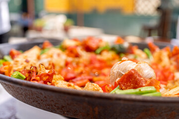 Cooking paella with chicken, tomatoes, green beans and garlic on a rooftop