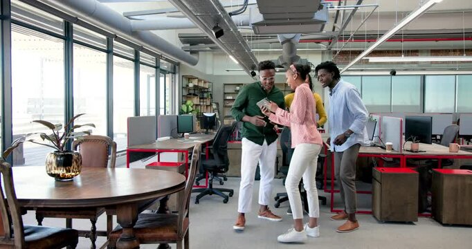 African American colleagues signing contract inside modern office, smiling with computer and plant