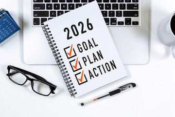 2026 Goal, Plan, Action checklist text on note pad with laptop, glasses and pen.