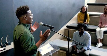 African American man speaking at podium in modern office, with African American women applauding