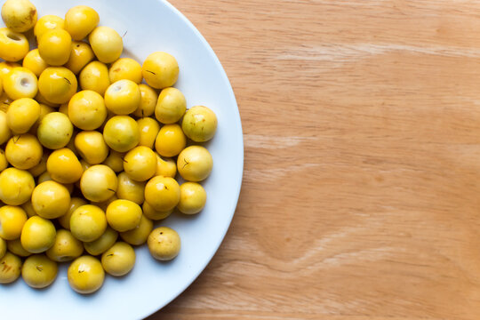 High resolution photo of fresh nance berries served on a simple white plate over wood, perfect for healthy eating, natural food, or tropical fruit stock.