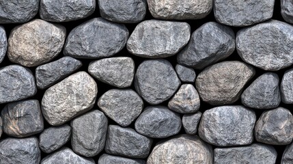 A textured stone wall composed of irregularly shaped stones in various shades of gray, providing a rustic and natural appearance.