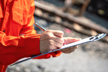 Close-up at safety supervisor's hand during writing on chemical safety checklist to verify the...