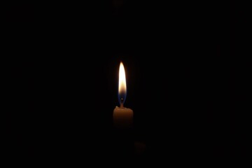 single lit candle in the dark