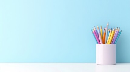 A colorful assortment of pencils in a white cup on a minimalist white desk against a light blue wall, and creating a clean and creative workspace.