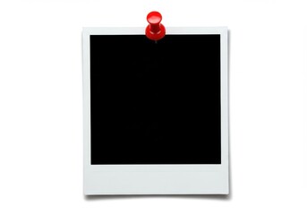 A polaroid picture with a black center attached to a wall with a red push pin on a white background