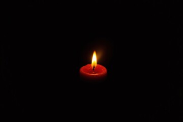 lit candle in the dark with a black background