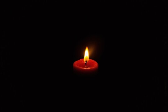 lit candle in the dark with a black background