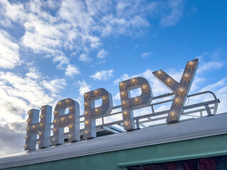 Lighting happy text on a roof with sky background copy space.