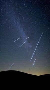 Meteors falling over dark hills at night
