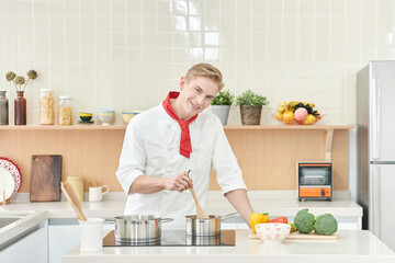 Young Chef Cooking in Modern Kitchen with Fresh Vegetables