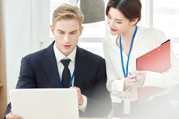 Obraz premium Multinational Business Colleagues Collaborating at Office Desk with Laptop and Documents