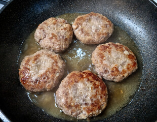 This is a frying pan where hamburger steaks are being cooked.
