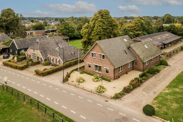 an aerial view of some houses in the country side area, with trees and bushes on either side of the road