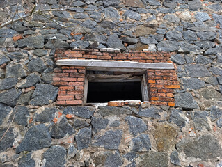 A brick wall with a small window in it