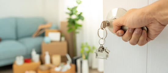 Moving house, relocation. The key was inserted into the door of the new house, inside the room was a cardboard box containing personal belongings and furniture. move in the apartment, banner