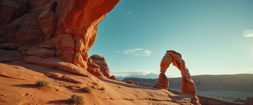 Majestic natural arch formations against a clear blue sky in a desert landscape, illuminated by golden sunlight