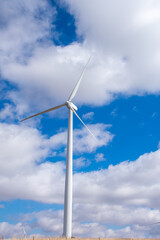 Wind turbine against a partly cloudy blue sky