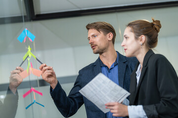 Team members collaborate on project planning using colorful sticky notes in a modern office setting