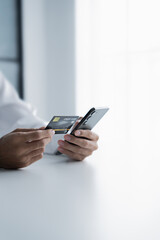 Asian male hold credit card and use mobile phone for online transactions.