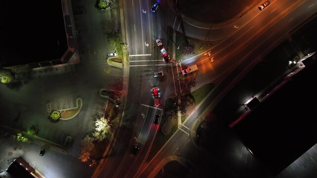 Cars on road arriving at accident scene on junction at night. aerial top down shot. Car crash with injured person in america.