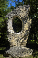 Photo frame. Round hole cut in wild limestone on background of a green park on sunny summer day....